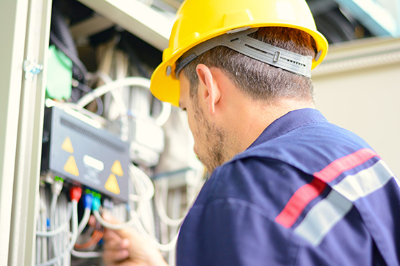 Man with yellow hard hat working on panel